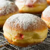 Puszyste pączki z dżemem, posypane cukrem pudrem, idealne jako zdrowe pączki dla dzieci.