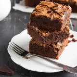 Stos puszystych brownie na talerzyku, idealne na zdrowe przekąski. Szukasz ciasta fit przepisy? Oto one!