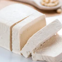 Kostka tofu, pokrojona w plastry, na białym talerzyku. Czy tofu to soja? Tak, to produkt z soi.
