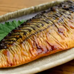 Pieczona makrela na talerzu, z zielonym liściem. Czy makrela jest zdrowa? Tak, to bogactwo kwasów omega-3!