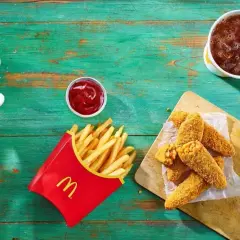 Chrupiące nuggetsy z serem i kukurydzą – to jest wege w maku! Obok frytki, ketchup i napój.