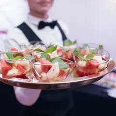 Kelner niesie tacę z owocowymi deserami. Zastanawiasz się, ile kosztuje catering firmowy?