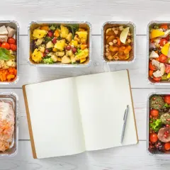Zdrowe posiłki w pudełkach, idealne na dietę pudełkową Wyszków. Planuj swoje posiłki z otwartym notatnikiem i długopisem.