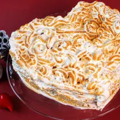 Serce z bezy, pyszne ciasto bez cholesterolu, ozdobione wzorami. Obok suszone kwiaty i czerwone serduszko.