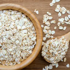 Płatki owsiane górskie w drewnianej misce i łyżce. Czy mają gluten? To pytanie nurtuje wiele osób.
