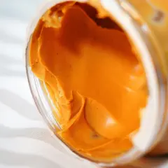 Zbliżenie na pomarańczowy proszek proteinowy w otwartym pojemniku.