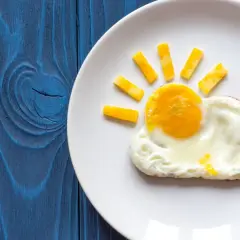 Słoneczko z jajka sadzonego na oleju i kawałków sera, obok chmurka z białka i pomidorek. Ciekawe, ile kalorii ma jajko sadzone na oleju w takiej formie?