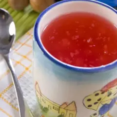 Czerwony kisiel na diecie w kubeczku z bajkowym wzorem, obok łyżeczka. Idealny na lekki deser.