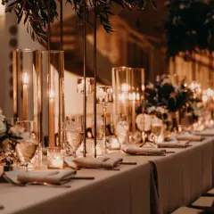 Elegancka sala bankietowa z długim stołem, świecami i kwiatami. Idealna na 50 urodziny, zastanawiasz się, ile za talerzyk na 50 urodziny?