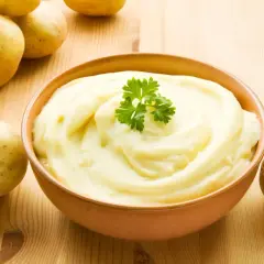 Aksamitne puree ziemniaczane, ozdobione natką pietruszki, obok świeżych ziemniaków. Idealne jako dodatek do obiadu.
