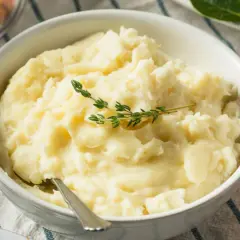 Puszyste puree ziemniaczane bez mleka, udekorowane gałązką tymianku. Idealne dla tych, którzy szukają sposobu, jak zrobić puree ziemniaczane bez mleka.