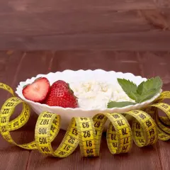 Twarożek z truskawkami i miętą, otoczony miarką krawiecką. Idealne śniadanie, gdy zastanawiasz się, ile kalorii na śniadanie przy odchudzaniu.