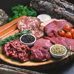 Mięso, kiełbaski, pomidorki i przyprawy na desce. Idealne składniki na dietę karniwora co jeść.