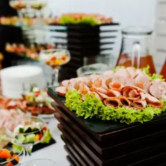Zastanawiasz się, ile kosztuje catering do domu? Na stole wędliny, sałatki i napoje, idealne na przyjęcie.