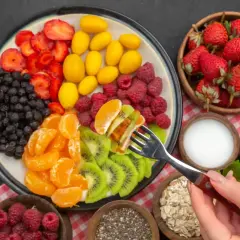 Kolorowy talerz z owocami: truskawki, jagody, maliny, mandarynki, kiwi, żółte owoce. Idealny jadłospis na dieta owocowa.