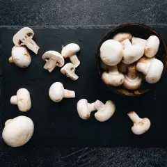 Świeże pieczarki na czarnej desce. Niskie pieczarki indeks glikemiczny sprawiają, że są idealne do zdrowej diety.