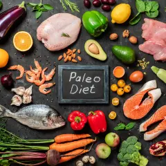 Na czarnej desce z napisem "Paleo Diet" ułożono składniki: ryby, mięso, owoce, warzywa i jajka. Idealny jadłospis dla zwolenników diety jaskiniowców.