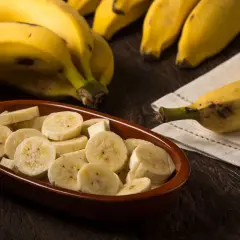 Kawałki banana w misce i cały banan obok. Pomyśl o tym, ile energii dostarcza jeden banan, kalorie to tylko jedna z jego zalet.