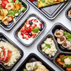 Różnorodne dania z cateringu dietetycznego Augustów: sałatka z krewetkami, jogurt z owocami, ryż z kurczakiem, warzywa i mięso.