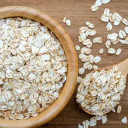 Płatki owsiane górskie w drewnianej misce i łyżce. Czy mają gluten? To pytanie nurtuje wiele osób.
