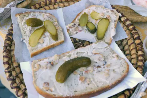 Chleb z grubą warstwą smalcu i ogórkami kiszonymi, podany na plecionej tacce. Klasyka polskiej kuchni, czyli co to smalec w najlepszym wydaniu.