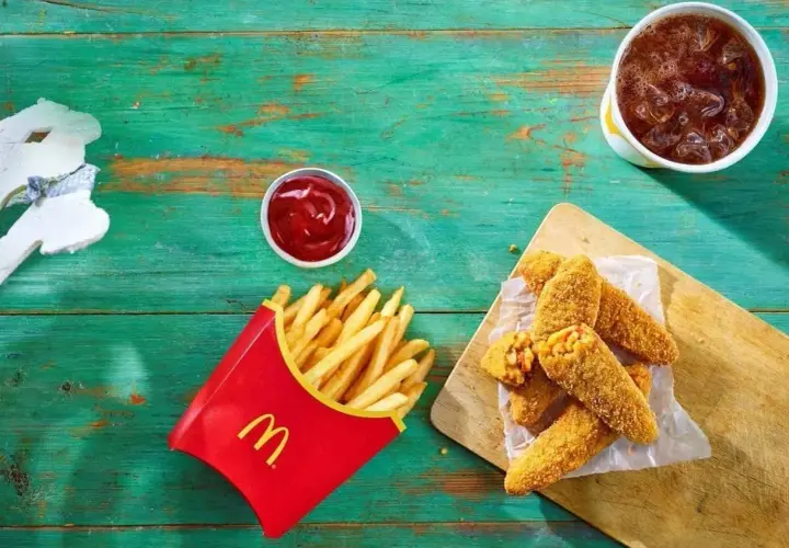 Chrupiące nuggetsy z serem i kukurydzą – to jest wege w maku! Obok frytki, ketchup i napój.