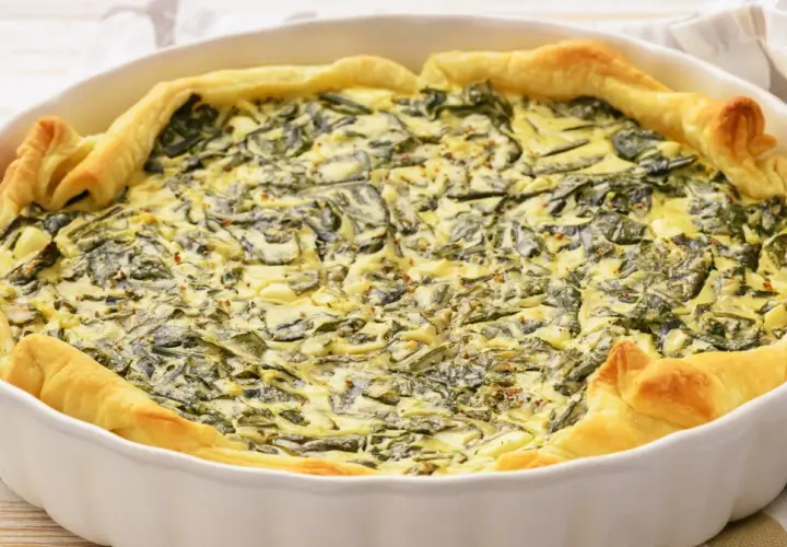 Pyszny quiche ze szpinakiem w białej formie, idealny pomysł na to, jak jeść szpinak. Złociste ciasto i kremowe nadzienie.