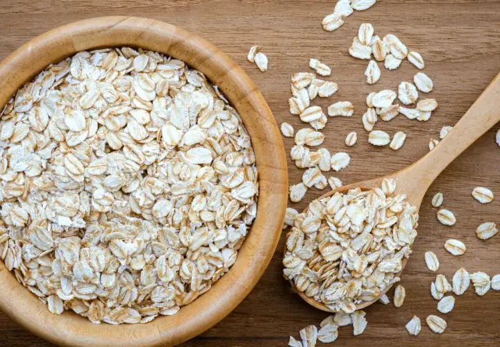 Płatki owsiane górskie w drewnianej misce i łyżce. Czy mają gluten? To pytanie nurtuje wiele osób.