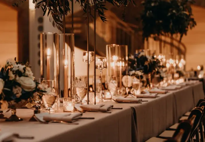 Elegancka sala bankietowa z długim stołem, świecami i kwiatami. Idealna na 50 urodziny, zastanawiasz się, ile za talerzyk na 50 urodziny?