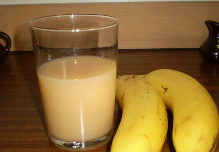 Szklanka orzeźwiającego soku z banana obok dwóch dojrzałych bananów. Idealny napój na szybkie śniadanie.