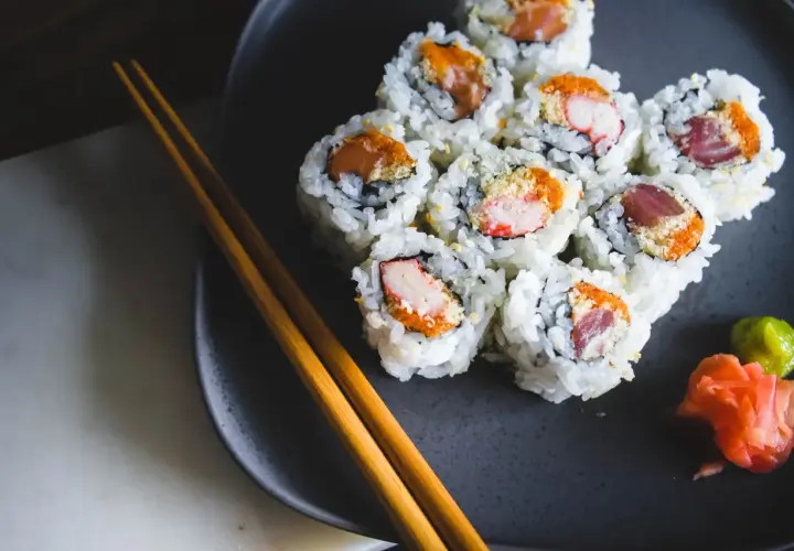Talerz z sushi, pałeczki i dodatki. Czy sushi tuczy? Zależy od składników i ilości ryżu.