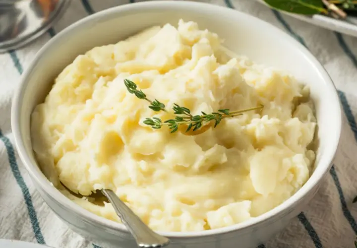 Puszyste puree ziemniaczane bez mleka, udekorowane gałązką tymianku. Idealne dla tych, którzy szukają sposobu, jak zrobić puree ziemniaczane bez mleka.