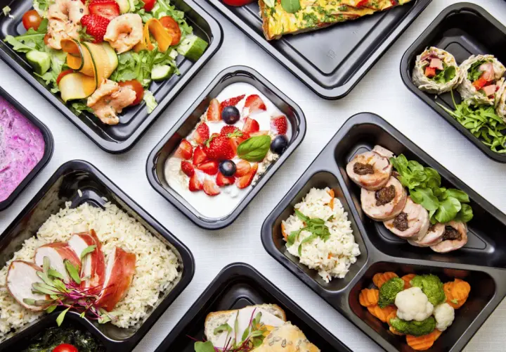Różnorodne dania z cateringu dietetycznego Augustów: sałatka z krewetkami, jogurt z owocami, ryż z kurczakiem, warzywa i mięso.