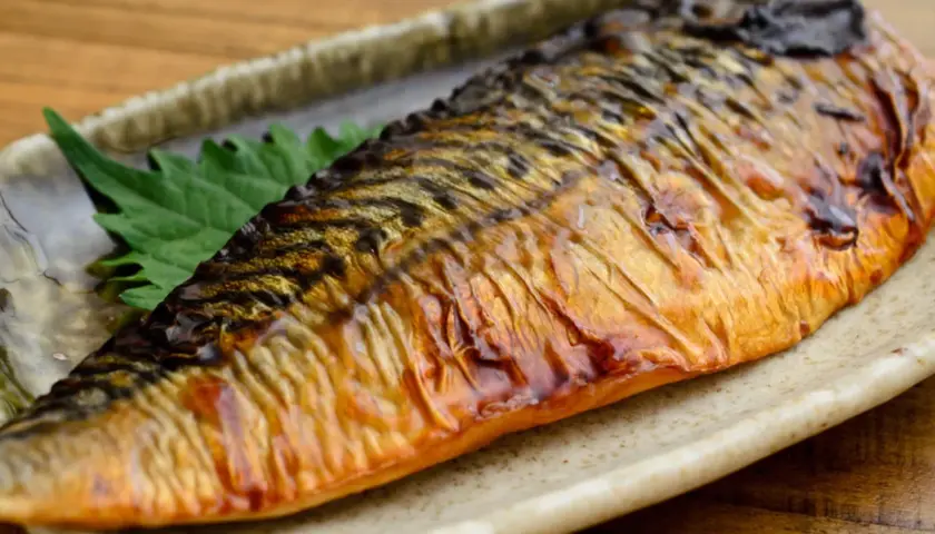 Pieczona makrela na talerzu, z zielonym liściem. Czy makrela jest zdrowa? Tak, to bogactwo kwasów omega-3!
