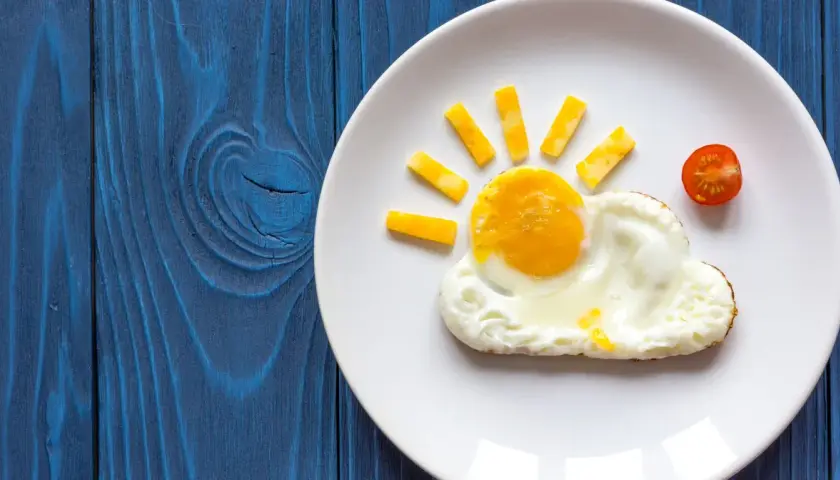 Słoneczko z jajka sadzonego na oleju i kawałków sera, obok chmurka z białka i pomidorek. Ciekawe, ile kalorii ma jajko sadzone na oleju w takiej formie?
