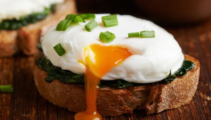 Jajko sadzone na grzance ze szpinakiem, z płynnym żółtkiem. Dwa jajka sadzone mają ok. 140 kcal.