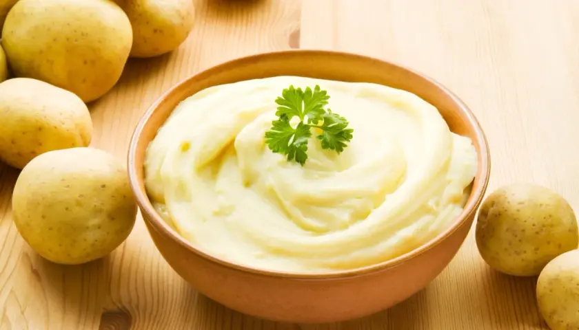 Aksamitne puree ziemniaczane, ozdobione natką pietruszki, obok świeżych ziemniaków. Idealne jako dodatek do obiadu.