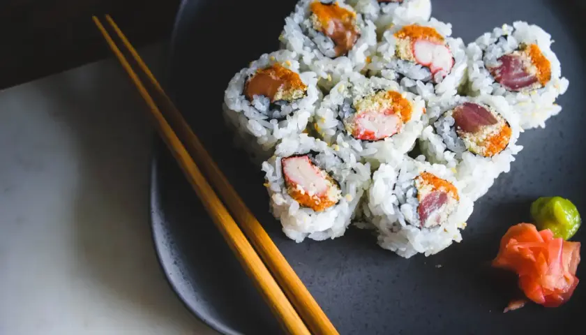 Talerz z sushi, pałeczki i dodatki. Czy sushi tuczy? Zależy od składników i ilości ryżu.