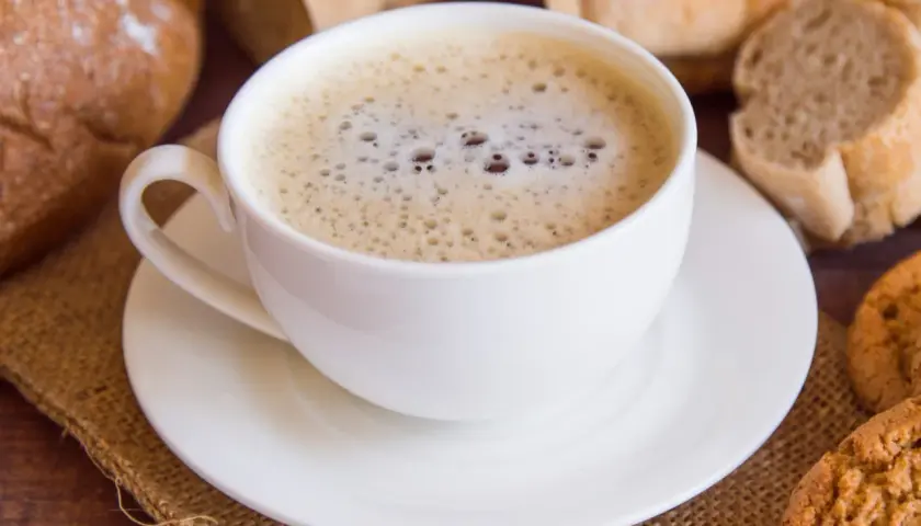 Kawa zbożowa z mlekiem, otoczona pieczywem i ciasteczkami, to zdrowa alternatywa dla tradycyjnej kawy.