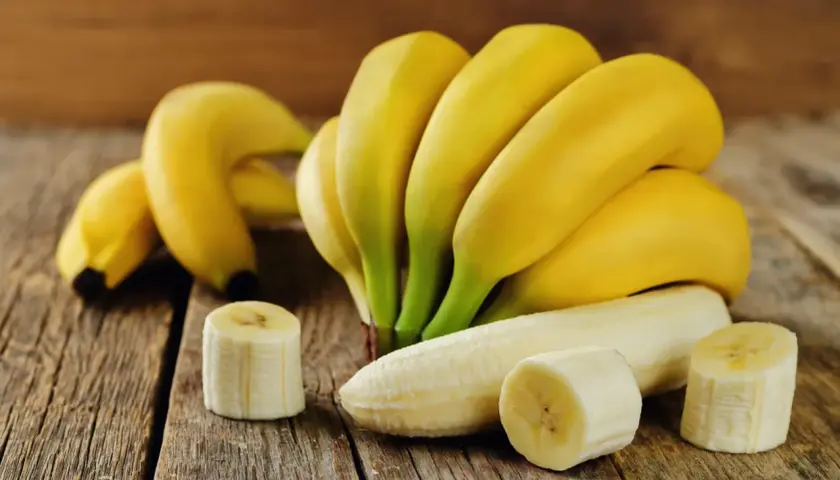 Pęczek dojrzałych bananów, jeden obrany, kilka plasterków. Idealny, duży banan kcal na zdrową przekąskę.