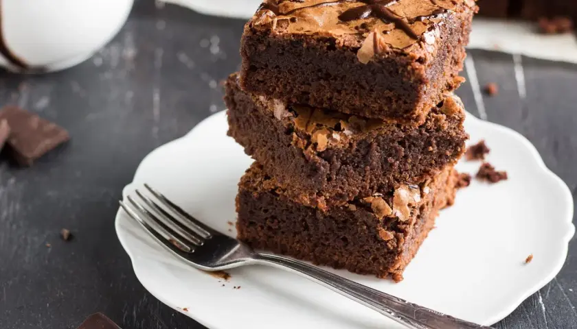 Stos puszystych brownie na talerzyku, idealne na zdrowe przekąski. Szukasz ciasta fit przepisy? Oto one!