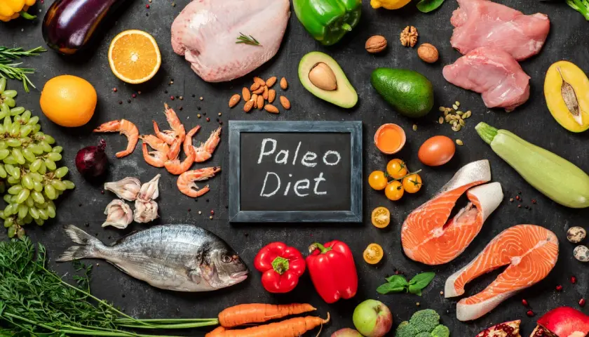 Na czarnej desce z napisem "Paleo Diet" ułożono składniki: ryby, mięso, owoce, warzywa i jajka. Idealny jadłospis dla zwolenników diety jaskiniowców.
