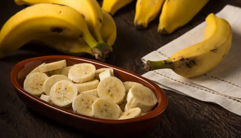 Kawałki banana w misce i cały banan obok. Pomyśl o tym, ile energii dostarcza jeden banan, kalorie to tylko jedna z jego zalet.