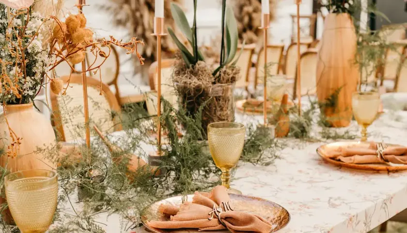Stół weselny z dekoracjami, kwiatami i zastawą stołową w stylu boho.