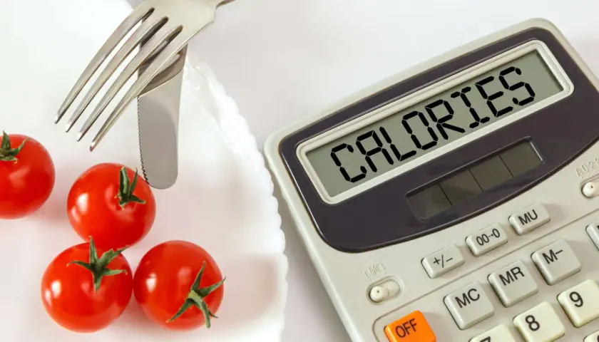 Pomidorki i kalkulator z napisem "CALORIES". Czy na keto trzeba liczyć kalorie? To pytanie zadaje sobie wiele osób.