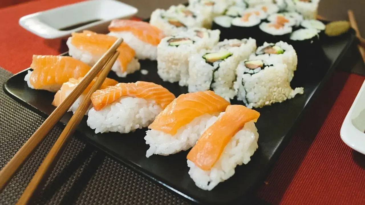Pyszne sushi na diecie: nigiri z łososiem i rolki z awokado na czarnej tacy, gotowe do spożycia.