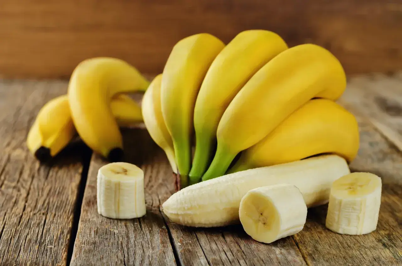 Pęczek dojrzałych bananów, jeden obrany, kilka plasterków. Idealny, duży banan kcal na zdrową przekąskę.