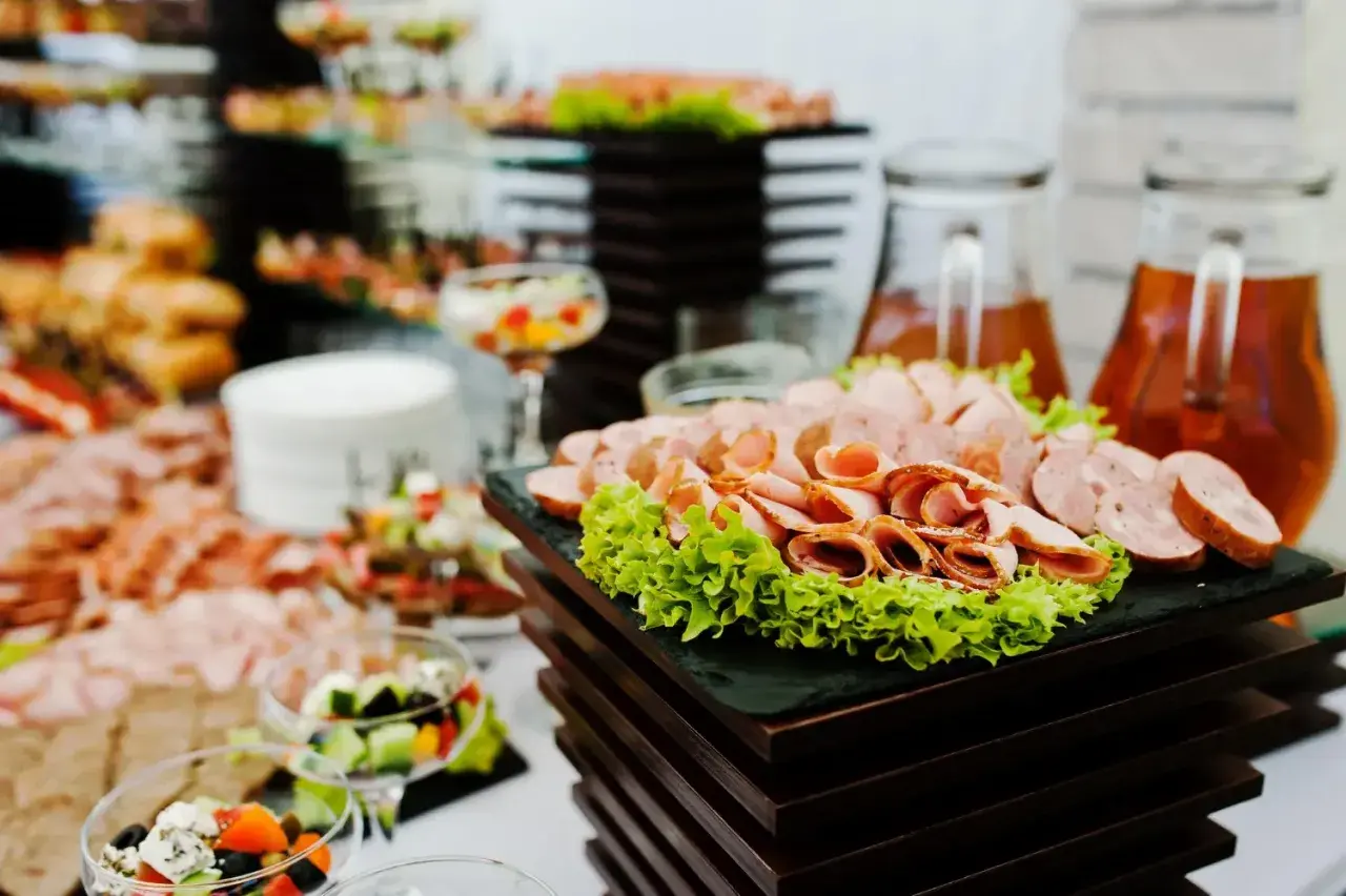 Zastanawiasz się, ile kosztuje catering do domu? Na stole wędliny, sałatki i napoje, idealne na przyjęcie.