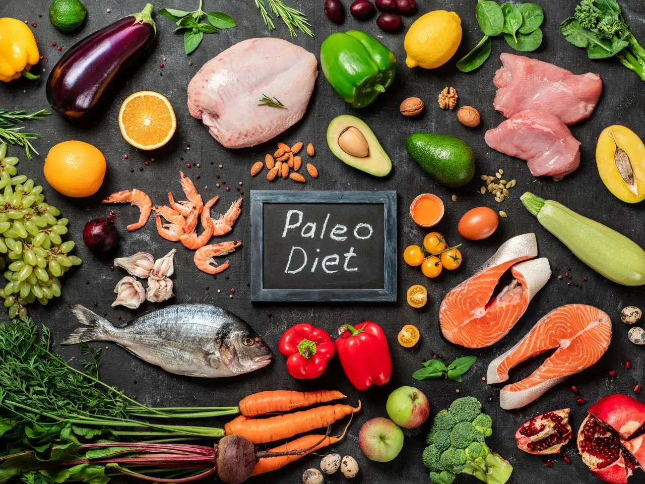 Na czarnej desce z napisem "Paleo Diet" ułożono składniki: ryby, mięso, owoce, warzywa i jajka. Idealny jadłospis dla zwolenników diety jaskiniowców.