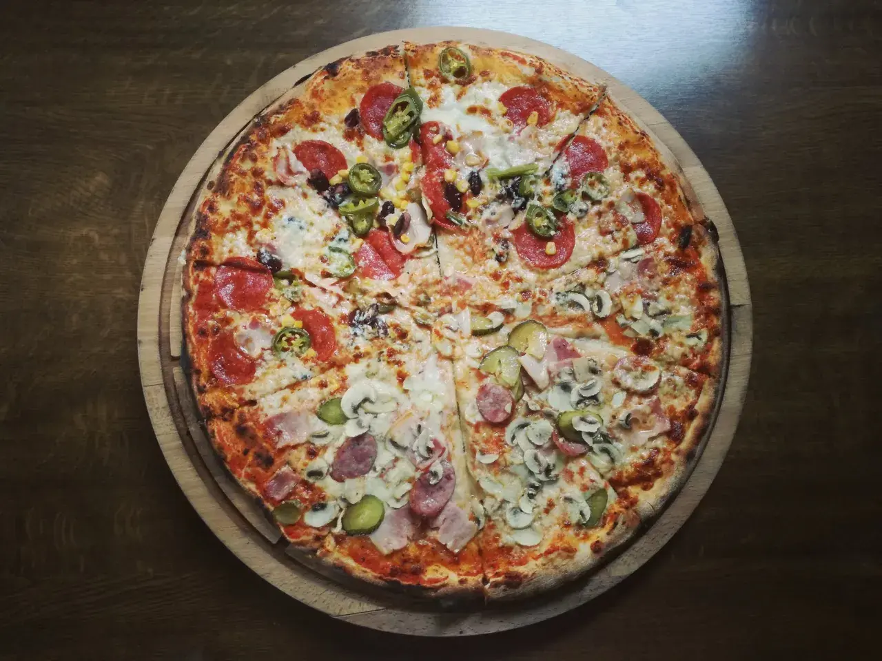 Apetyczna pizza na cienkim cieście z różnymi dodatkami: salami, pieczarki, kukurydza, papryczki jalapeno i ogórek. Zastanawiasz się, ile kalorii ma pizza na cienkim cieście?